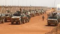 Gepanzerte Militärfahrzeuge stehen hintereinander bereit zur Abfahrt auf dem Wüstenboden Malis