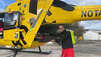 Ein Mann in Rettungsdienstkleidung schiebt eine Trage in einen Hubschrauber