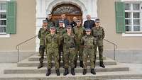 Eine Gruppe Soldaten steht mit drei Zivilisten auf einer Treppe