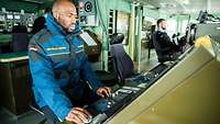 Ein Soldat schaut auf die elektronische Seekarte auf der Brücke eines Schiffes