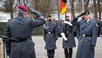 Zwei Soldaten grüßen sich militärisch, dahinter zwei Soldaten mit der Kommandofahne.