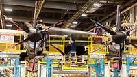 Five employees lift one of the leading edges of the aircraft into place.