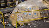 A curved metal structure stands in a production hall.