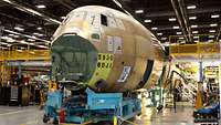 The front part of the fuselage without the nose is situated in an assembly hangar.