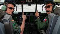 A German pilot and a French co-pilot sit in the cockpit, smile at the camera and give the thumbs up.