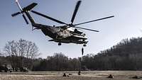 Aus einem fliegenden Hubschrauber seilen sich Soldaten auf eine Wiese ab und gehen in Deckung.