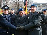 Drei Soldaten stehen nebeneinander und gratulieren sich. Im Hintergrund drei weitere Soldaten