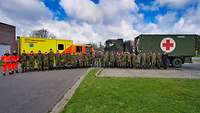 Viele Soldaten stehen vor einem Rettungswagen und einem militärischen LKW