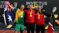 Die drei erstplatzierten Sportler posieren Arm in Arm mit ihren Medaillen und Flaggen