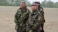 Brigadegeneral Dirk Faust steht mit zwei Soldaten im Gelände