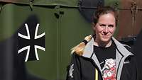 Eine junge Frau in Zivil steht vor einem großen Bundeswehr-Kraftfahrzeug