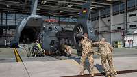 Soldaten schieben einen Hubschrauber H145M LUH SOF über die Heckluke in einen A400M.