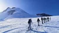 Soldaten marschieren auf Skiern hintereinander auf einem schneebedeckten Berg.