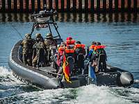 Soldaten fahren mit Zivilisten in einem Speedboot.