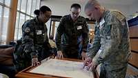 Three soldiers looking into a tactical map