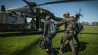 Soldaten geleiten einen Mann zu einem wartenden Hubschrauber vom Typ NH 90