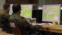 Soldaten sitzen hinter PC-Bildschirmen an Schreibtischen. 