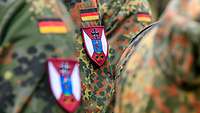 Soldaten stehen in Reihe und Glied, an ihrer Uniform das Wappen des ABC-Abwehrregimentes 1.