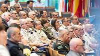 International audience sits in the lecture hall and looks towards the lecture