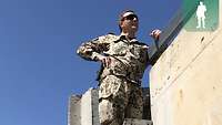 Ein Soldat steht auf einer Leiter neben zwei T-Walls und kontrolliert den Dachaufbau
