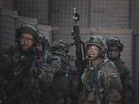 Mehrere Soldaten stehen mit dem Gewehr in einer Befestigung aus Sand und Stahl.