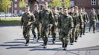 Ein Gruppe Soldatinnen und Soldaten marschiert in Formation.