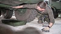 Ein Soldat untersucht den Unterboden eines Fahrzeugs.