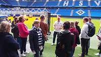 Menschengruppe steht am Spielfeldrand eines Fussballstadions.