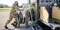 Ein Soldat in ABC-Schutzkleidung schiebt Kleidungsstücke in die Heißgas-/Heißdampfkammer eines TEP 90.