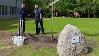 Ein israelischer und ein deutscher Luftwaffengeneral geben sich vor einem frisch gepflanztem Baum die Hände