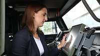 A young woman in a military vehicle, looking at a screen