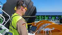 A man is preparing the launch of a drone on board of a vessel