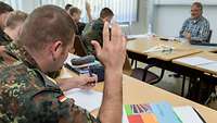 Mehrere Soldaten sitzen beim Unterricht in einem Klassenzimmer