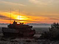 Ein Kampfpanzer in der Morgendämmerung vor einer Buschgruppe