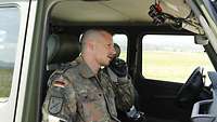 Ein Soldat hat ein Funkgerät in einem Auto am Ohr