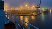 Eine Hafenanlage mit Lichtern und Kränen im Dämmerlicht