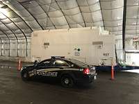 Ein amerikanisches Polizeiauto steht vor einem weißen Container