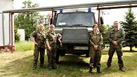 Zwei Soldatinnen und zwei Soldaten posieren vor einem Bundeswehr-Krankenwagen