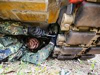 Ein Soldat repariert die Ketten eines Schützenpanzers Mader im freien Gelände.