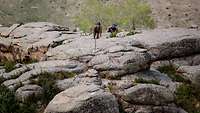 Zwei mongolische Soldaten schauen eine steile Felswand herauf.