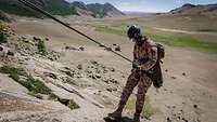 Ein mongolischer Soldat seilt sich auf felsigem Untergrund ab.