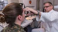 Ein Arzt untersucht die Augen im Rahmen der Eignungsfeststellung von Anwärtern für den fliegerischen Dienst.