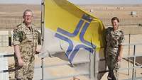 Militärseelsorgerin Maike Seelhorst und Militärpfarrer Martin Söffing holen die Flagge der Katholischen Militärseelsorge ein