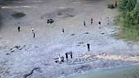 Am Strand haben mehrere Personen "Danke" in den Sand geschrieben und winken.