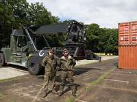 Zwei Soldaten stehen vor einem Flurförderfahrzeug.