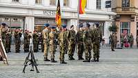 Soldaten stehen links und rechts aufgereiht vor der Truppenfahne