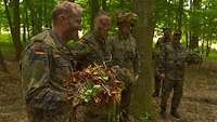 Fünf Männer in Uniform im Wald mit Gefechtshelm und Tarnschminke im Gesicht