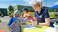 Zwei Erzieherinnen sitzen mit kleinen Kindern an einem Tisch und basteln.