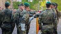 Bei einem feierlichen Gelöbnis legen sechs ausgewählte Soldaten die Hand auf die Nationalflagge.