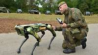 Ein Soldat mit einem Roboter, der einem Hund ähnelt.